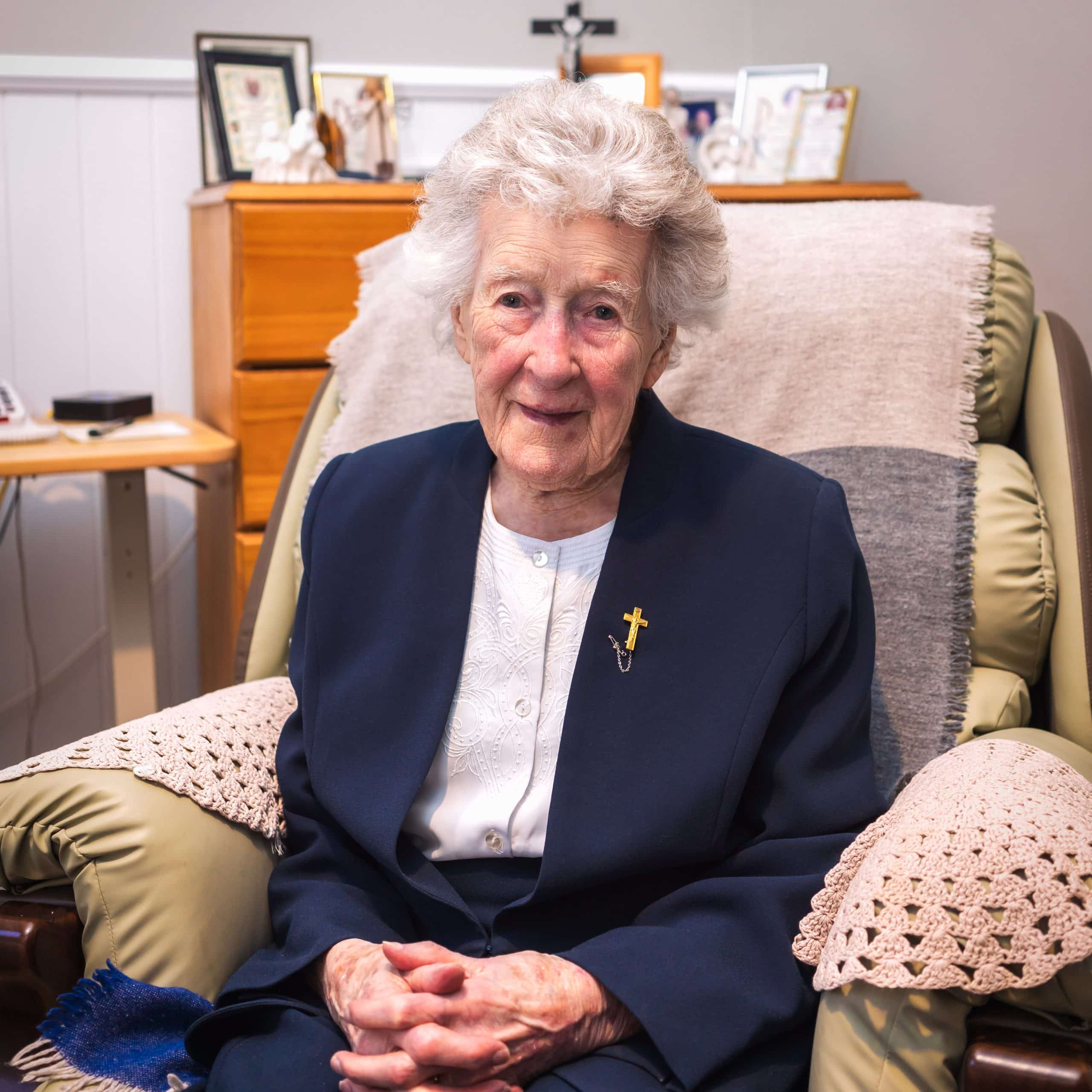 An older woman sits in an armchair